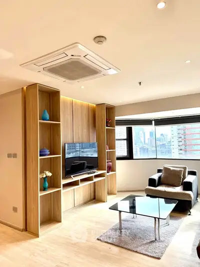 Modern living room with city view, featuring stylish furniture and built-in wooden shelves.