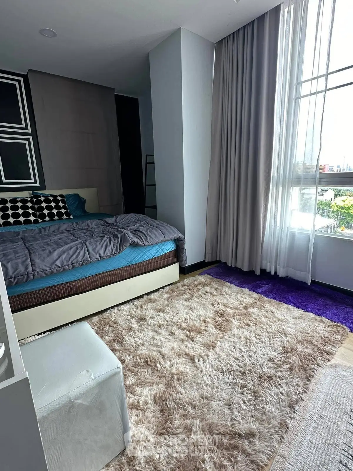 Modern bedroom with plush carpet and large window offering natural light.