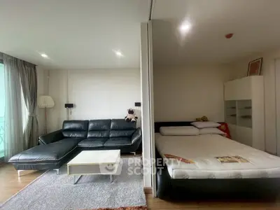 Modern studio apartment with sleek black leather sofa and cozy bed, perfect for urban living.