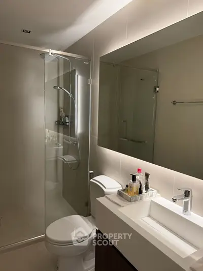 Modern bathroom with glass shower and sleek vanity in contemporary home.