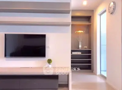 Modern living room with sleek TV setup and stylish shelving in a bright apartment.
