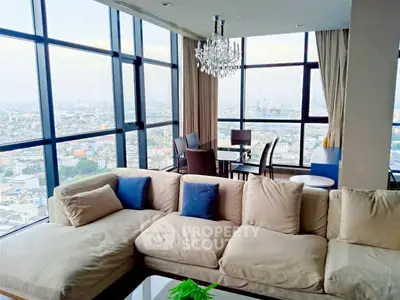 Luxurious corner unit living room with panoramic city views and elegant chandelier.