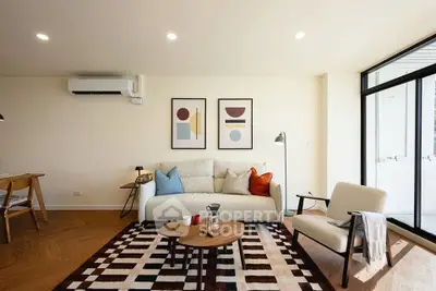 Modern living room with stylish decor, cozy seating, and natural light from large windows.