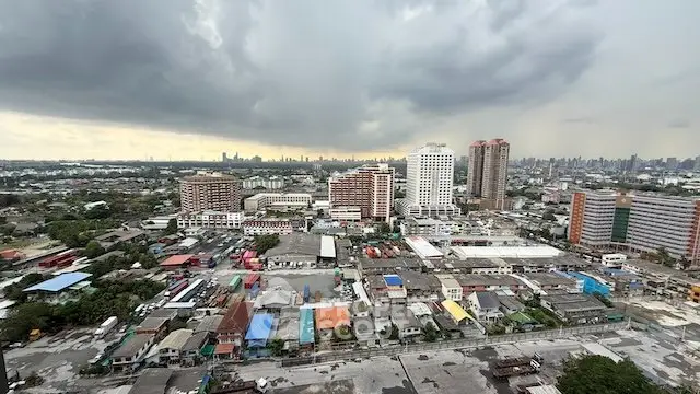 Panoramic cityscape view showcasing diverse urban architecture under a dramatic cloudy sky.