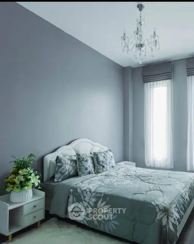 Elegant bedroom with floral bedding and chandelier in modern apartment