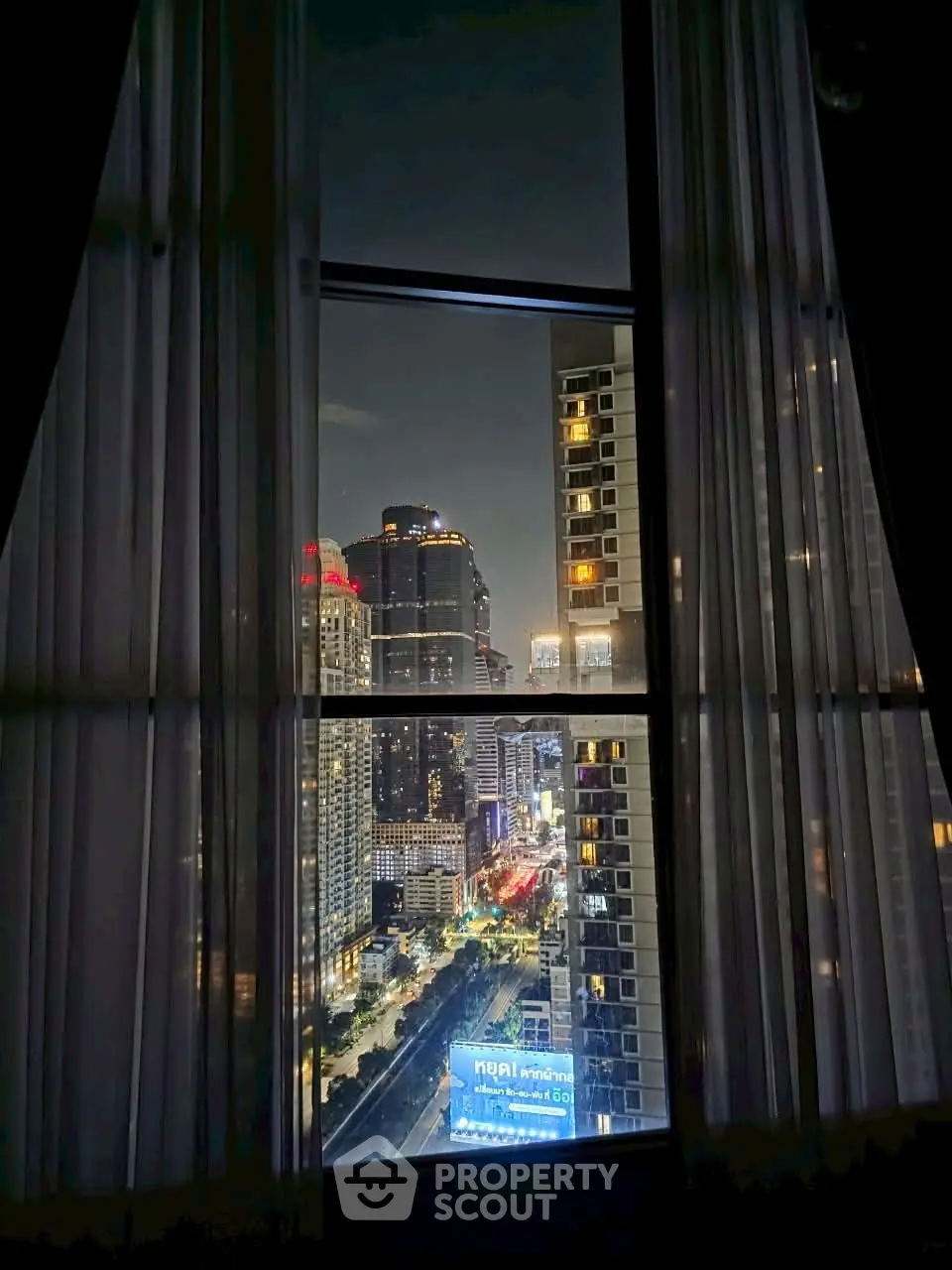 Stunning cityscape view from high-rise window at night, showcasing vibrant urban lights.