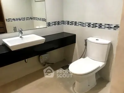 Modern bathroom with sleek black countertop and stylish tile accents.