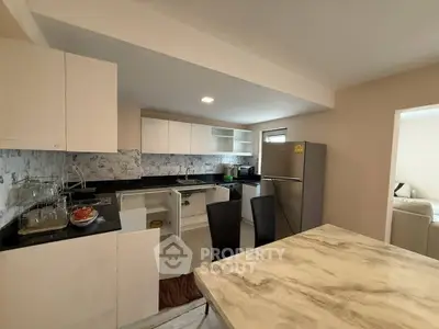 Modern kitchen with marble countertop and stainless steel appliances in a cozy apartment.