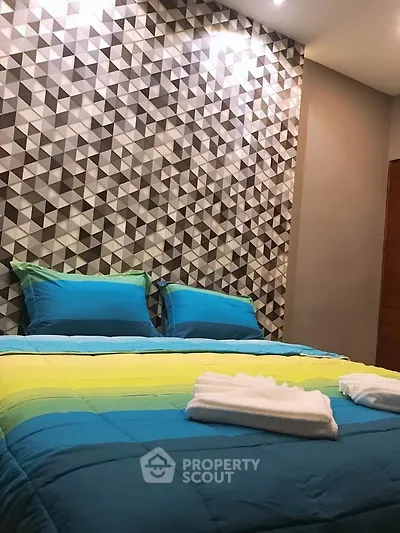 Stylish bedroom with geometric accent wall and vibrant bedding