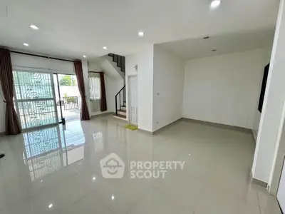 Spacious modern living room with large windows and staircase