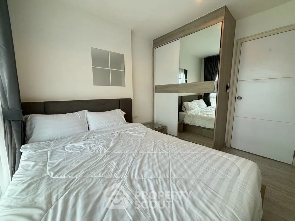 Modern bedroom with mirrored wardrobe and cozy bedding in a stylish apartment.