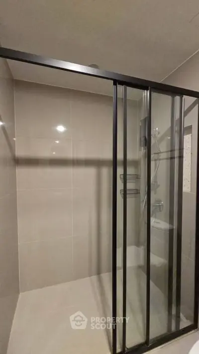 Modern bathroom with sleek glass shower enclosure and neutral tiles.
