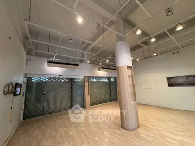 Spacious commercial space with modern lighting and wooden flooring, ideal for retail or office use.