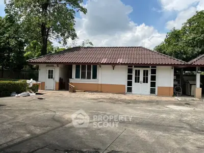 Charming single-story house with spacious driveway and lush greenery.