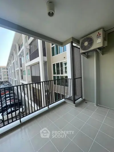 Spacious balcony with modern railing overlooking a contemporary apartment complex.