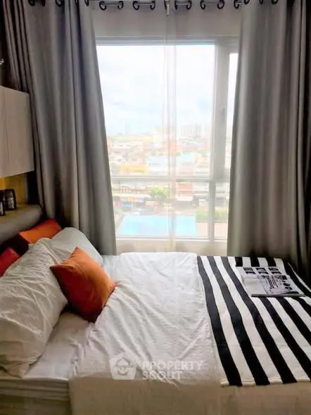 Cozy bedroom with large window offering a stunning city view, featuring modern decor and comfortable bedding.