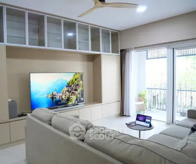 Spacious living room with modern entertainment setup and balcony view