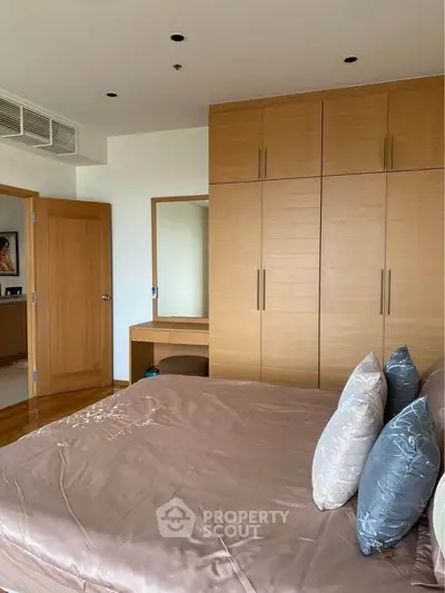 Spacious bedroom with elegant wooden wardrobe and cozy bedding