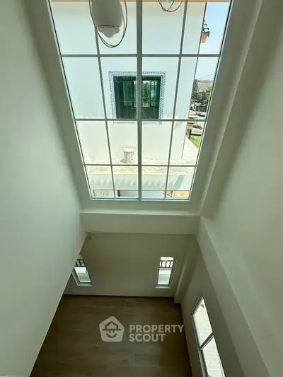 Spacious room with high ceiling and large windows offering ample natural light.