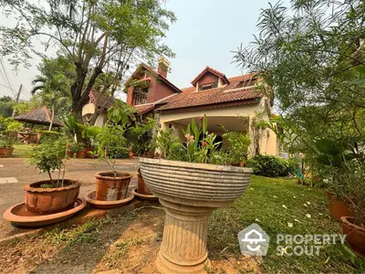 Charming estate with terracotta roof tiles nestled among lush greenery, featuring a serene garden and classical outdoor planters.