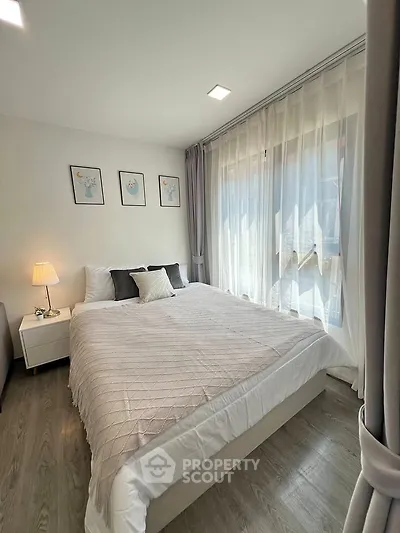Cozy bedroom with large window and elegant decor, perfect for relaxation.