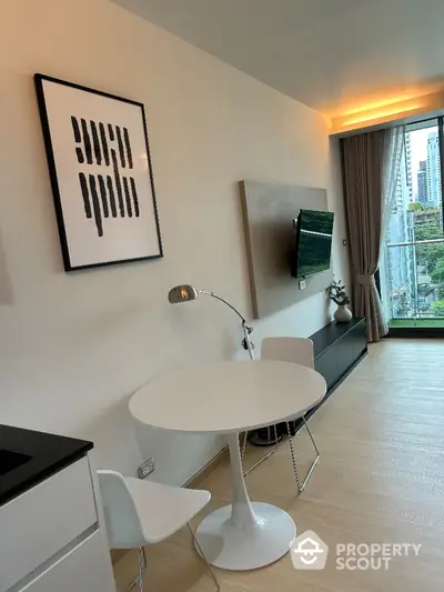 Modern living room with sleek decor and city view, featuring a stylish round table and wall-mounted TV.