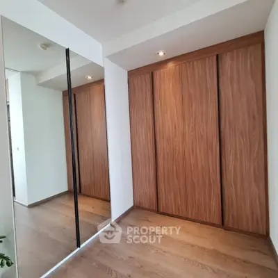 Spacious modern bedroom with elegant wooden wardrobe and mirrored closet doors
