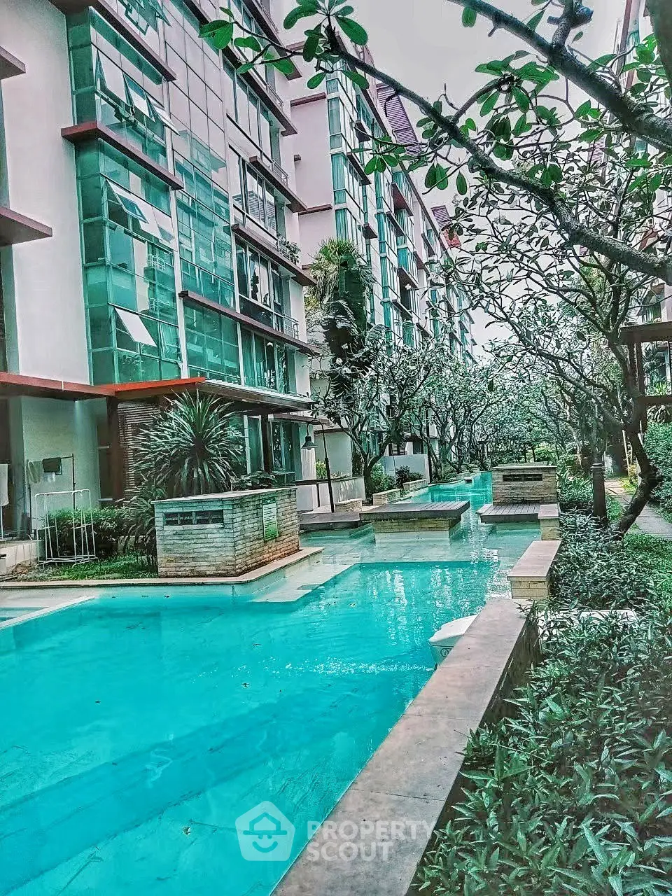 Luxurious apartment complex with stunning pool and lush greenery, perfect for modern living.
