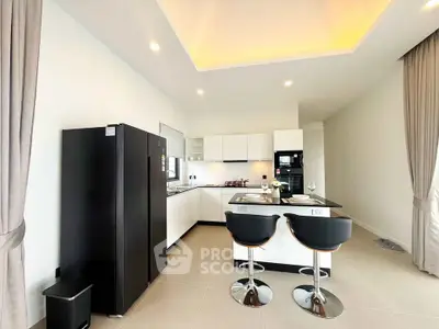 Modern kitchen with sleek black appliances and stylish bar seating in a contemporary apartment.