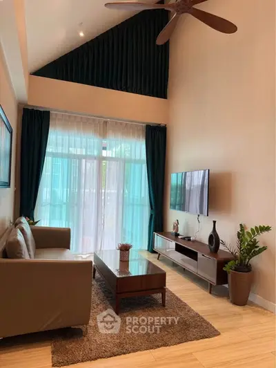 Elegant living room with high ceiling, modern furniture, and large windows for natural light.