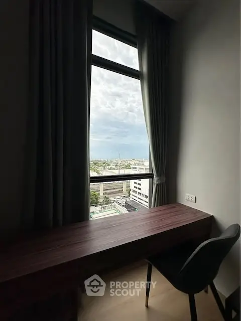 Modern study room with city view from large window, featuring sleek desk and chair.