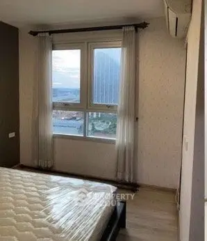 Spacious bedroom with large window offering city view, featuring modern decor and air conditioning.