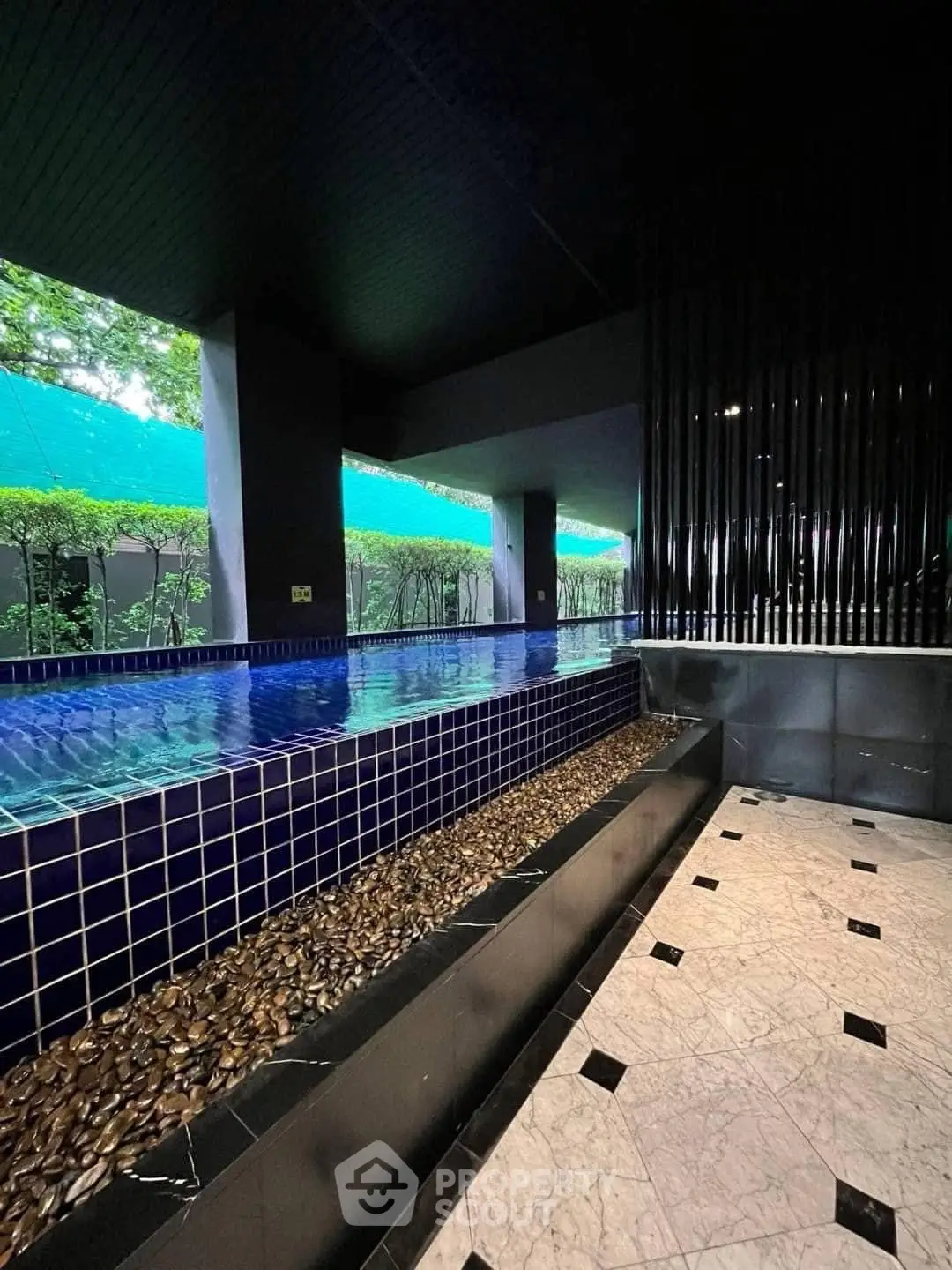 Luxurious indoor pool with elegant tile design and serene garden view