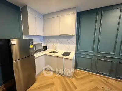 Modern kitchen with sleek cabinetry and stainless steel appliances in stylish apartment.
