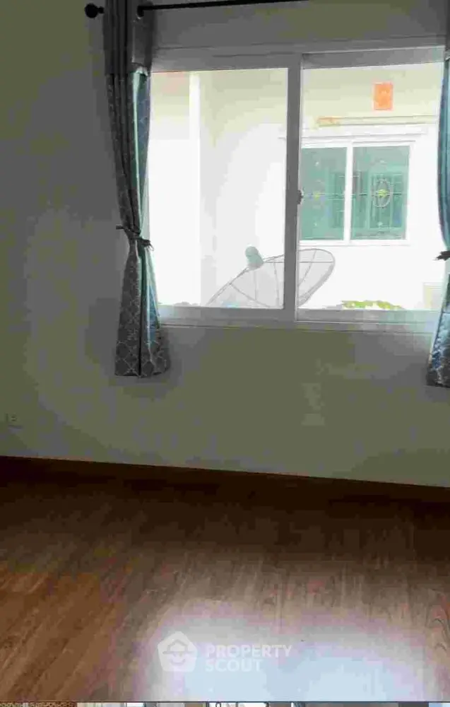 Bright room with wooden flooring and window view, ideal for cozy living space.