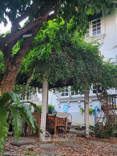 Charming garden with lush greenery and outdoor seating in a serene residential setting.