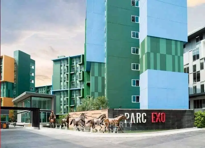 Modern apartment complex with colorful facade and horse sculptures at entrance.