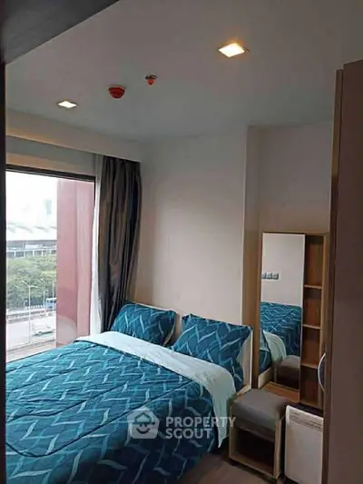 Cozy bedroom with large window and modern decor in urban apartment.