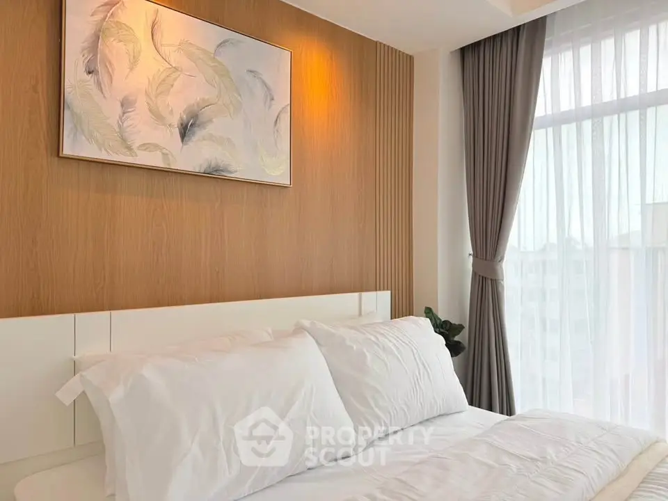 Elegant bedroom with modern decor and large window offering natural light.
