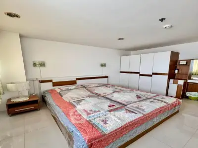 Spacious bedroom with modern furniture and large bed in a bright, minimalist design.