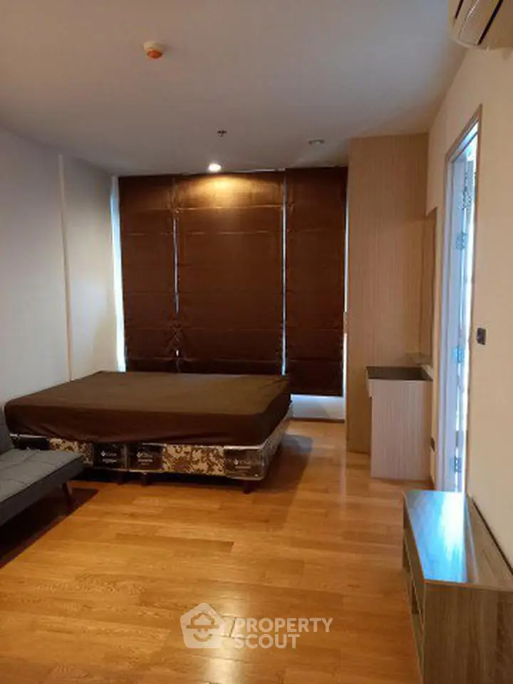 Spacious bedroom with wooden flooring and large windows in modern apartment