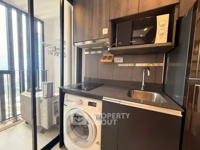 Modern kitchen with washing machine and microwave in sleek apartment