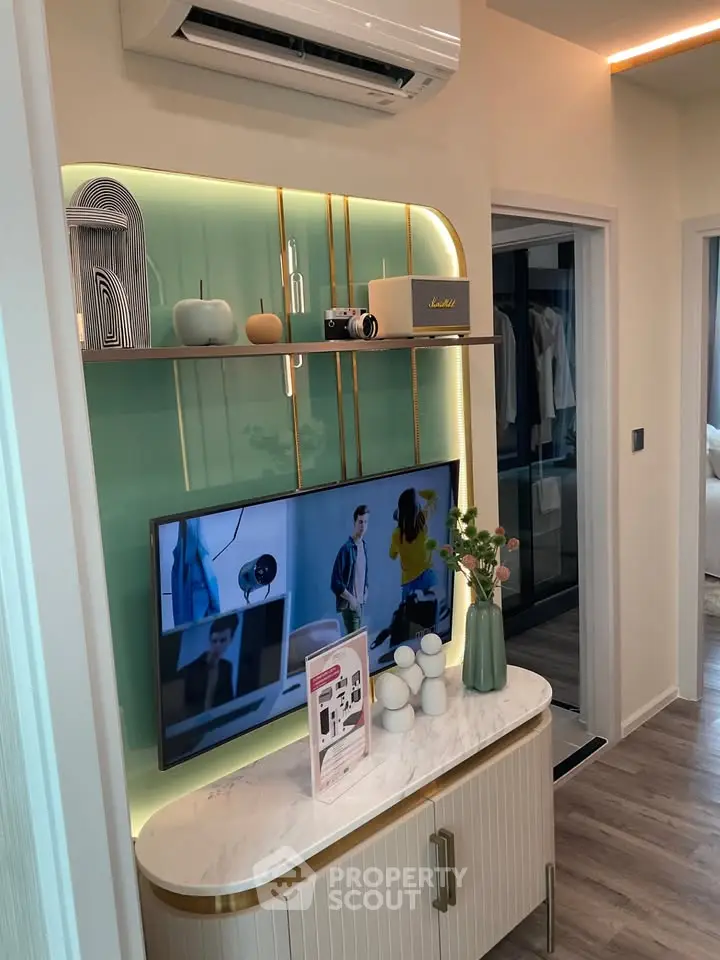 Modern living room with stylish decor and wall-mounted TV, featuring sleek storage and ambient lighting.