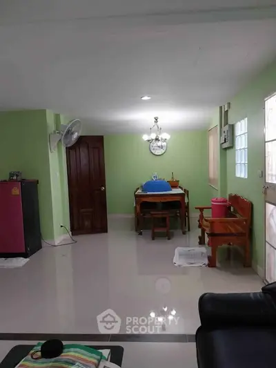 Spacious living area with green walls and elegant wooden furniture.