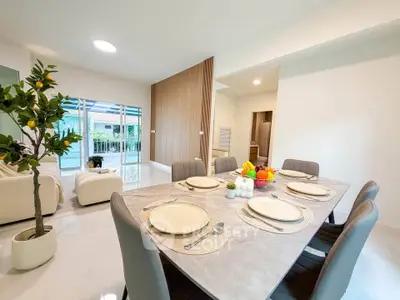 Spacious modern dining area with elegant table setting and view of cozy living room.