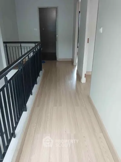 Spacious corridor with wooden flooring and modern railing in a contemporary home.