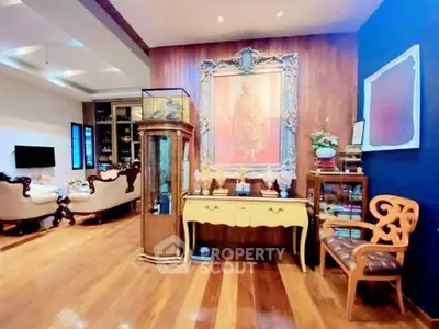 Elegant living room with classic furniture and polished wooden floors, featuring a large framed artwork.
