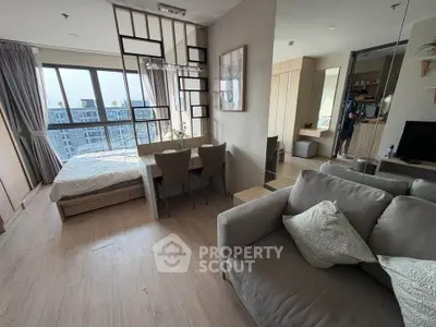 Modern studio apartment with open layout, featuring a cozy living area and large windows for natural light.