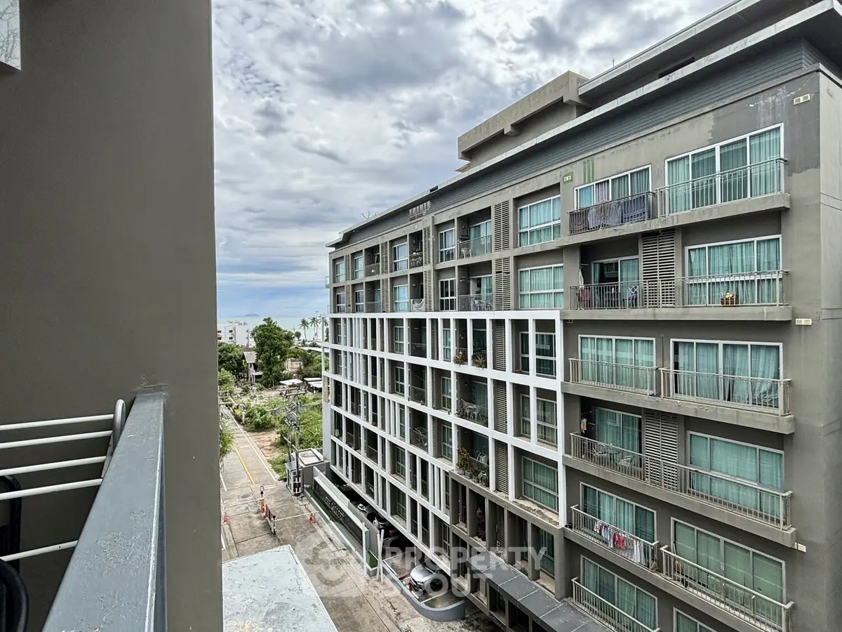 Modern apartment building with balconies and street view, showcasing urban living.
