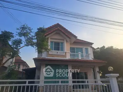 Charming two-story house with a red-tiled roof and lush greenery, perfect for family living.